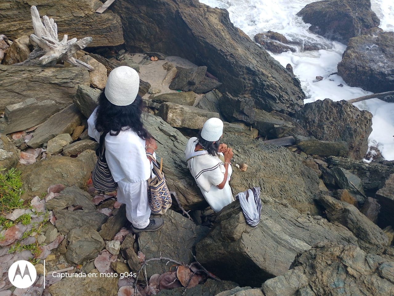 Two Arhuaco people sitting on coastal rocks overlooking the Caribbean sea